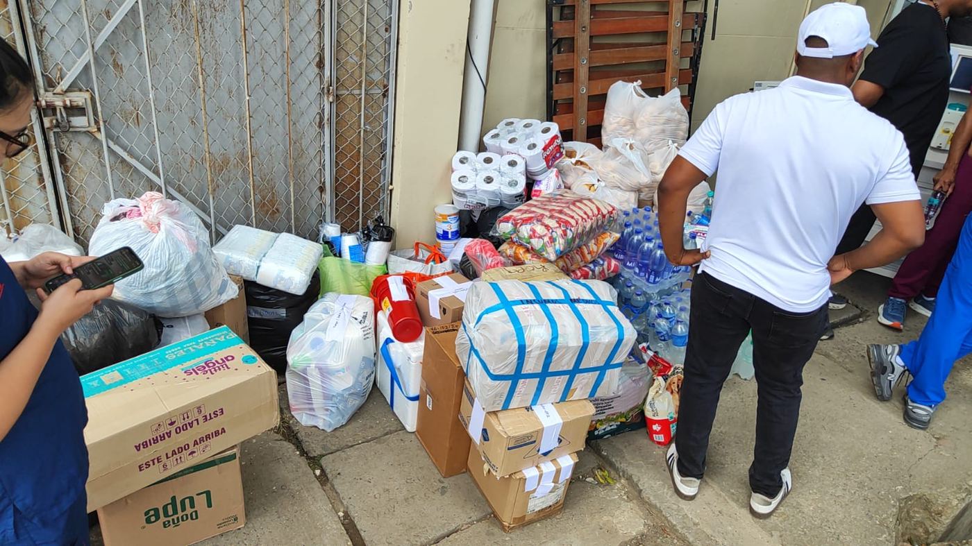 Voluntarios organizando alimentos, agua y elementos de aseo donados.